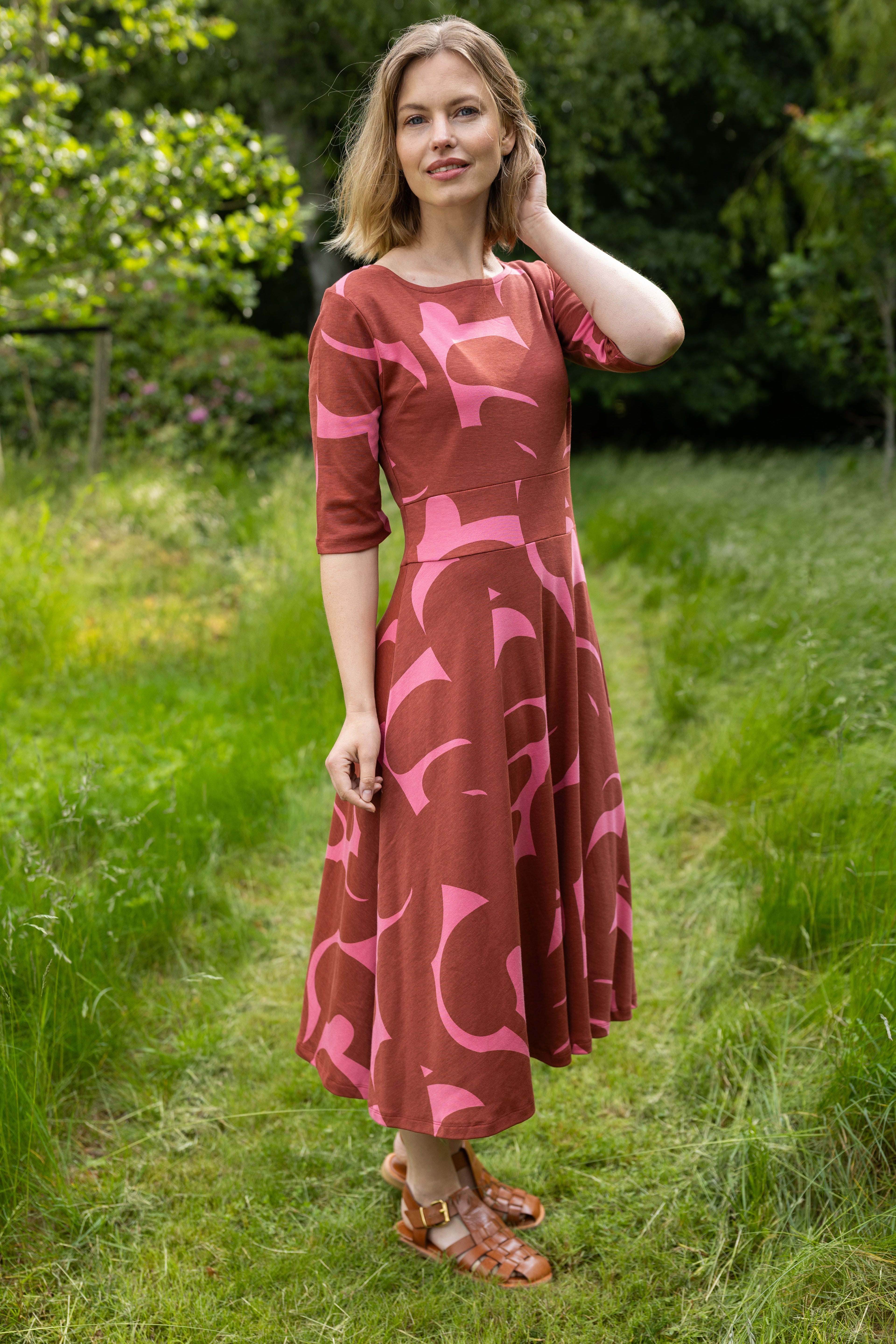 Sød kjole med abstrakt mønster i brændt rød og pink til kvinder