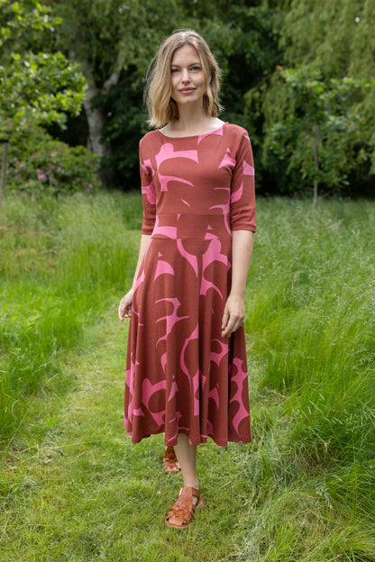 Sød kjole med abstrakt mønster i brændt rød og pink til kvinder