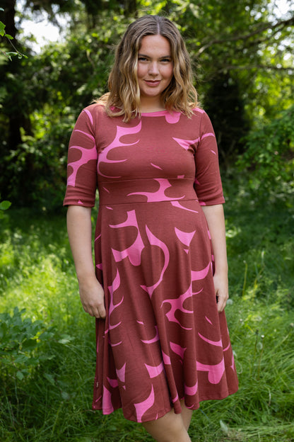 Sød kjole med abstrakt mønster i brændt rød og pink til kvinder