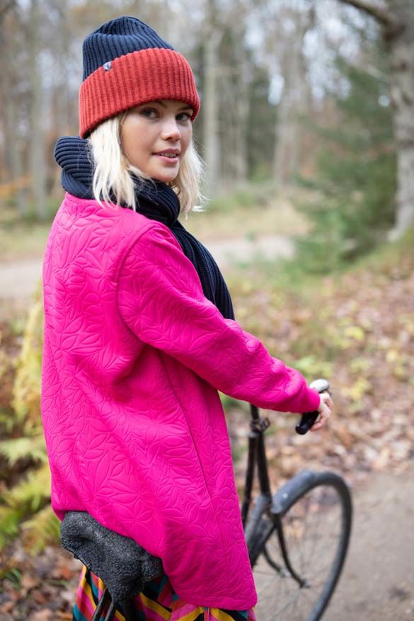 Kvinde på cykel med pink termojakke 